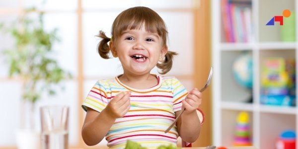 Child holding a spoon, colorful setting and eating nutritious food based on vancouver pediatric therapist suggestion